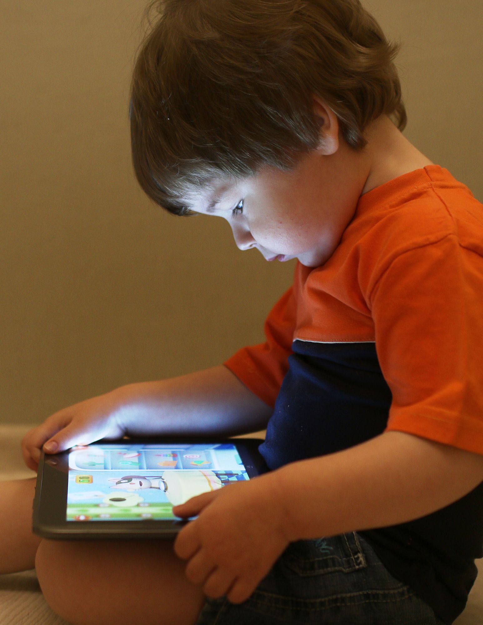 toddler with brown hair watches tablet in lap