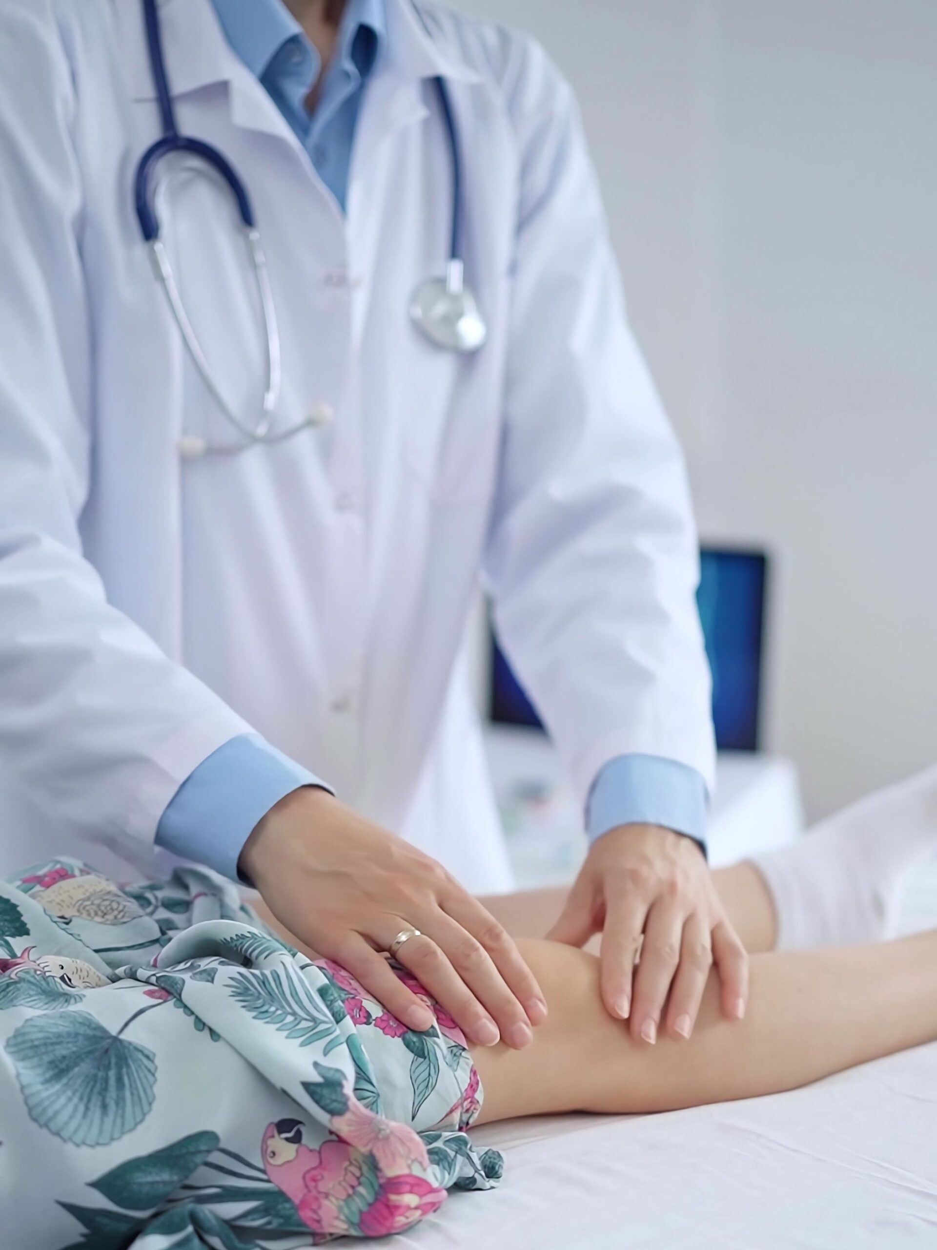 doctor wearing white coat examines a child's outstretched leg