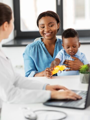 parent with child on lap talks to a doctor at a computer