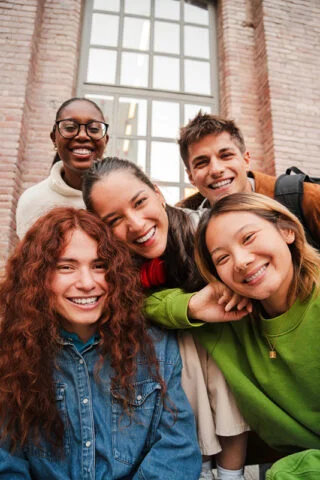 A group of teenage friends stand together outside a building