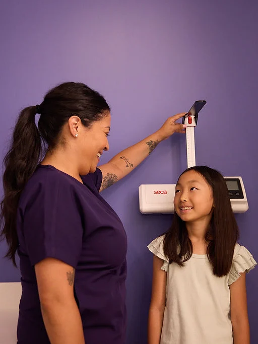 Patient is smiling while being measured by CHOC staff member at appointment