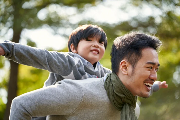 dad gives 5-year-old son a piggy back ride 