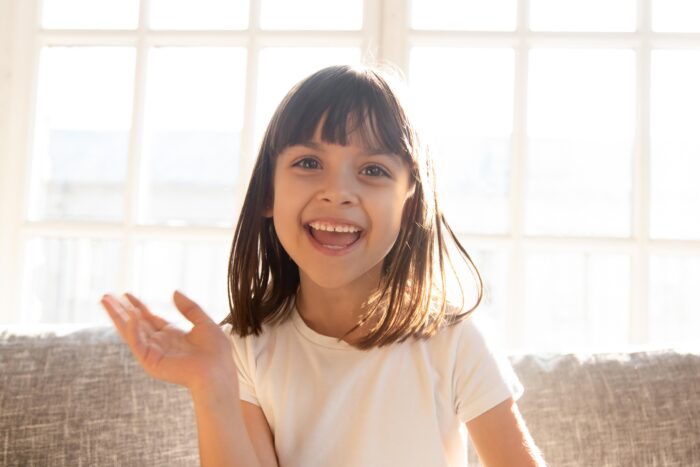 Girl smiling and waving in front of window