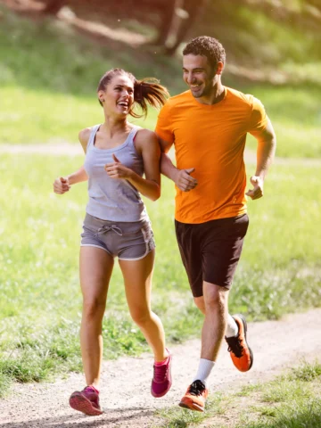 man and woman run on trail together 