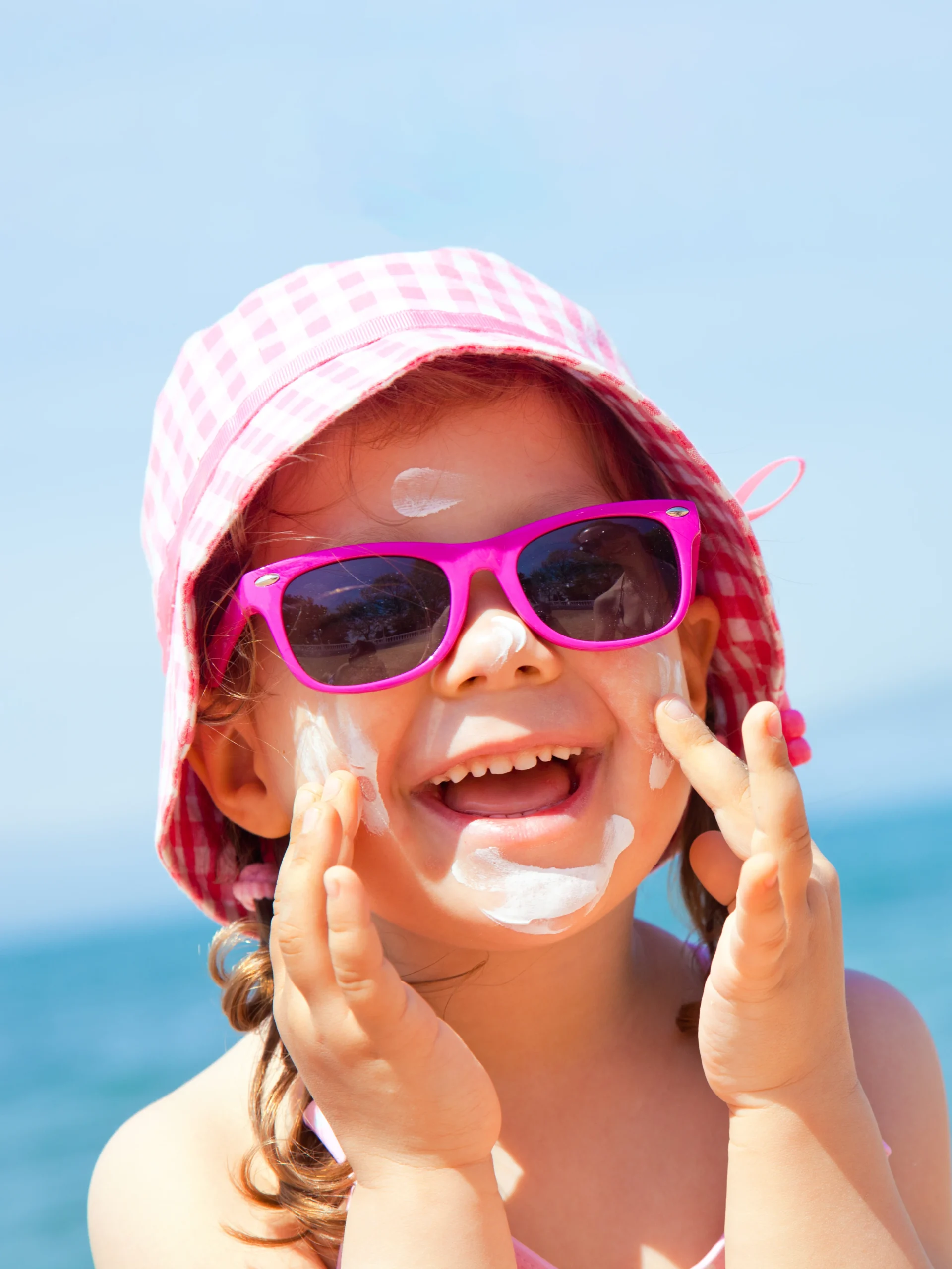 young girl putting on sunscreen