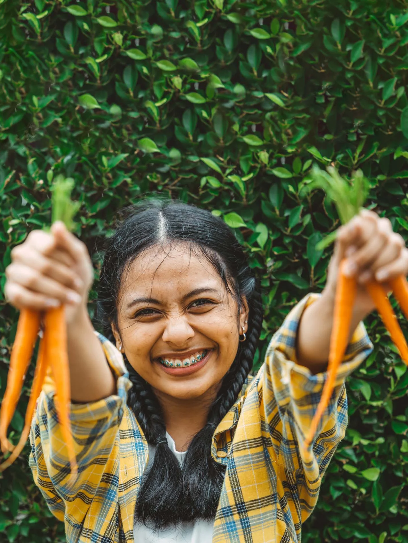 Teen holding up carrots from garden