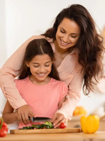 Parent and child eating healthy and cutting vegetables together