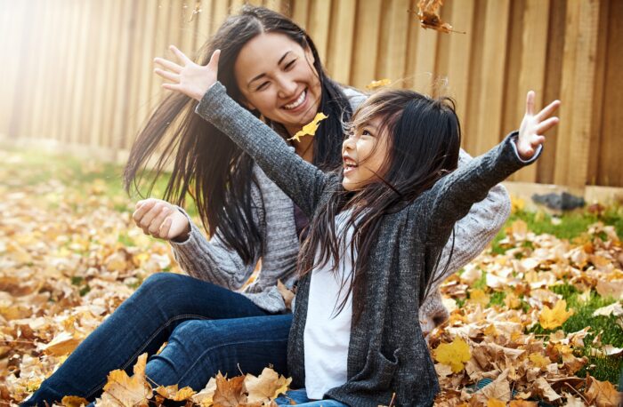 Parent and child throwing leaves