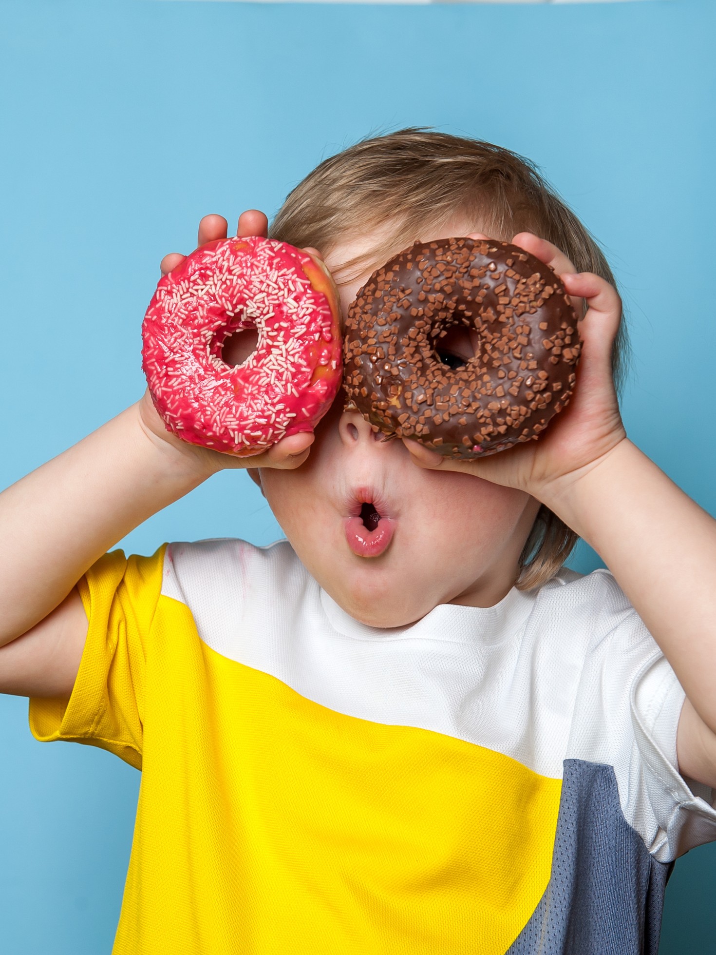 Kid holding up two donuts