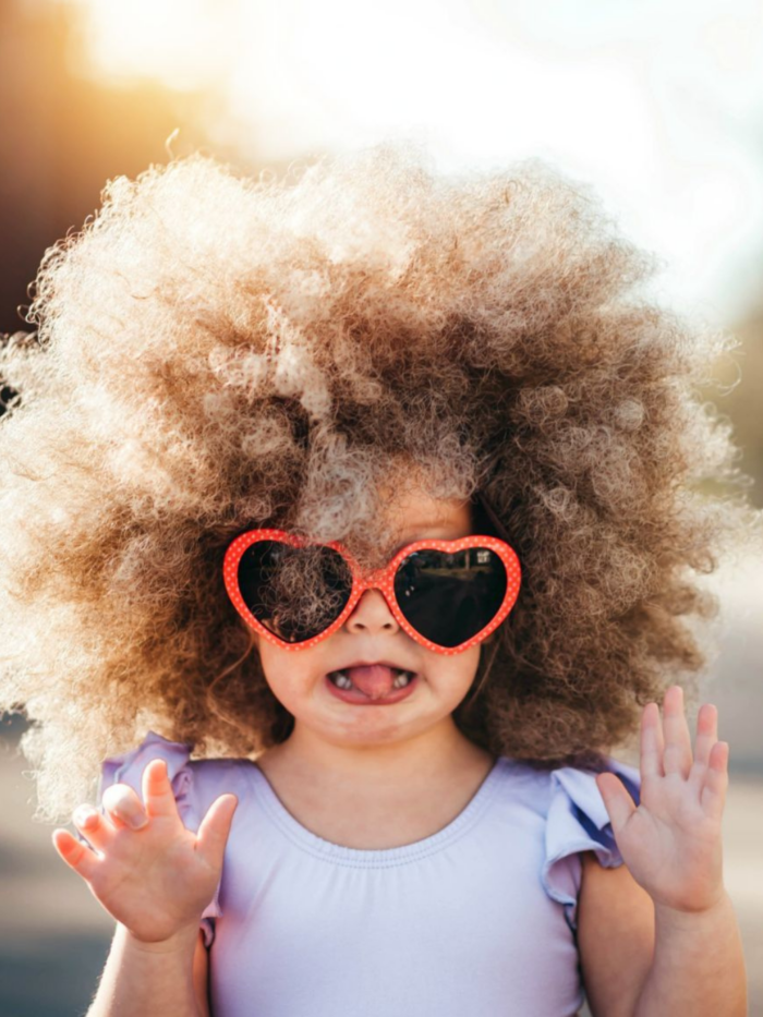 Little girl with heart shaped sunglasses sticking her tongue out