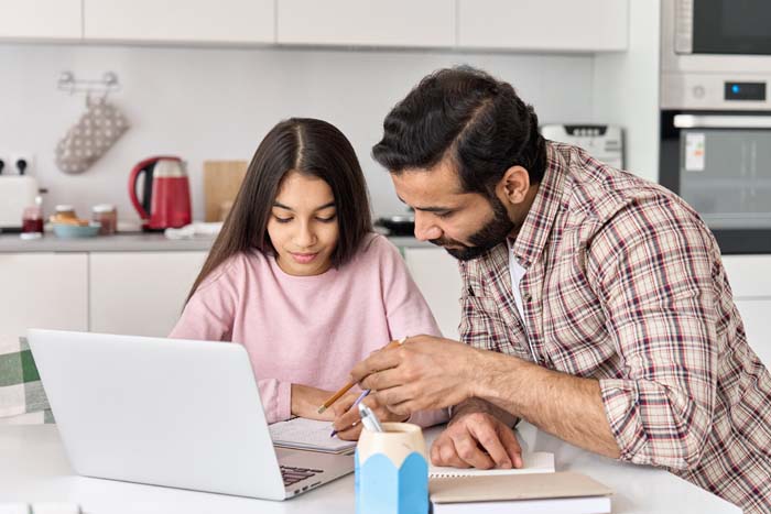 Dad and daughter look at computer together