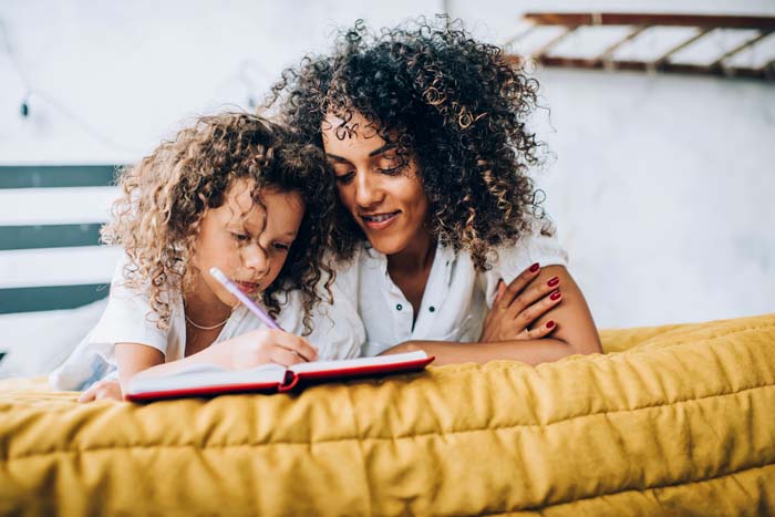 Mom and daughter writing in notebook 