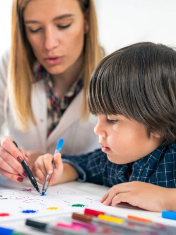 Psychologist and child coloring together 