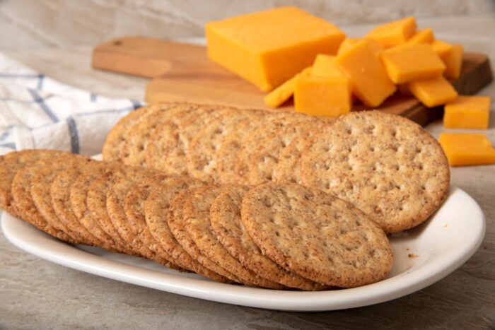 A plate of whole grain crackers with sliced sharp cheddar cheese