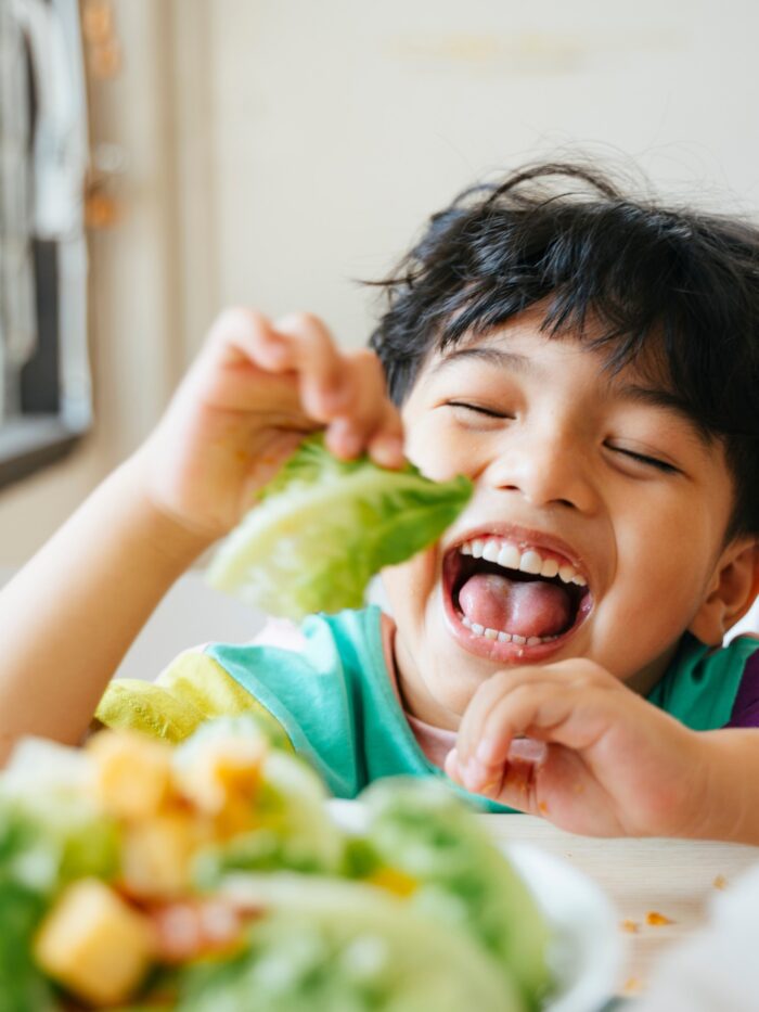 Little boy enjoys his breakfast with cos in salad.