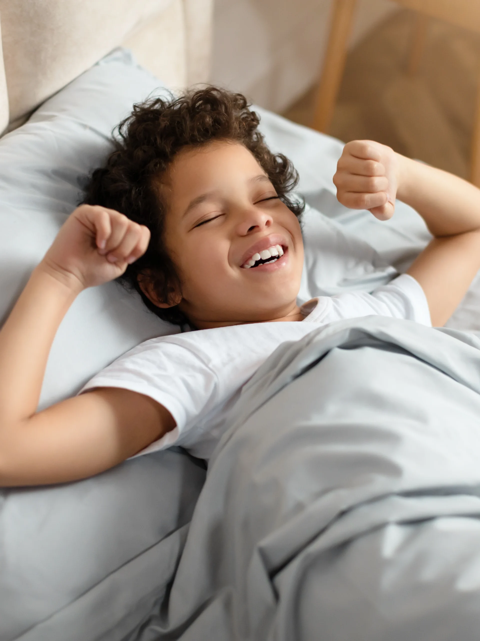 child smiling while laying in bed