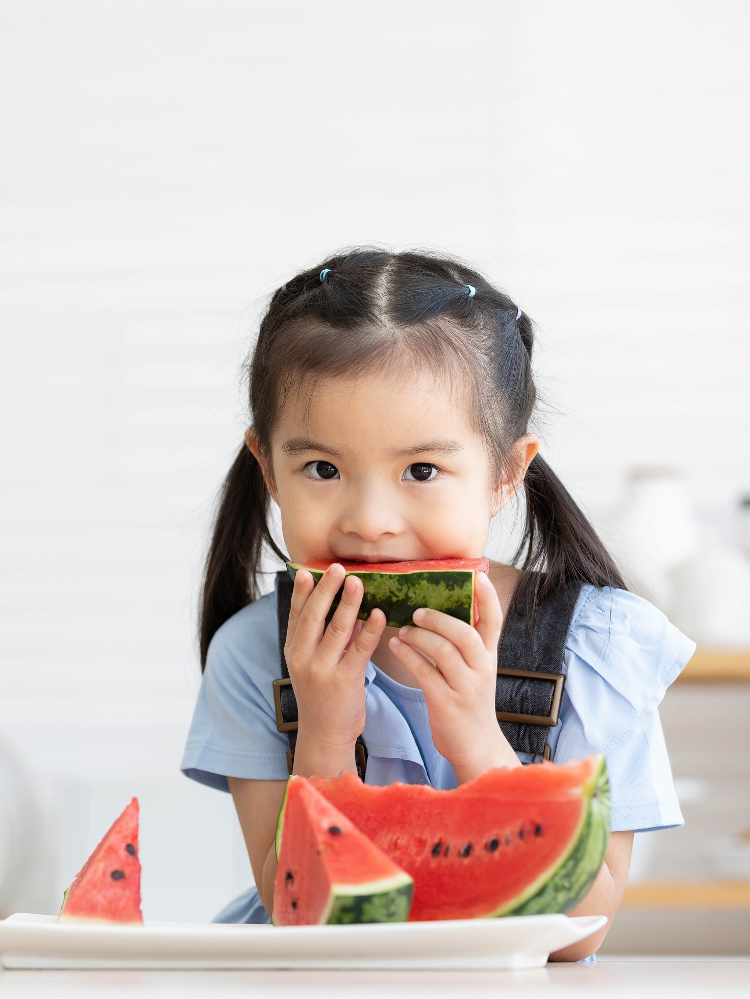 cute little child girl eating slice watermelon in the kitchen