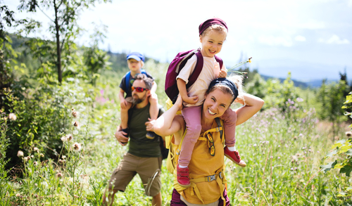 Family with small children hiking outdoors in summer nature.
