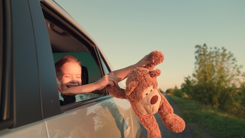 little girl with toy bear. happy face child daughter from window with teddy bear. happy family. prepare kids for summer travel by bringing their stuffed animals