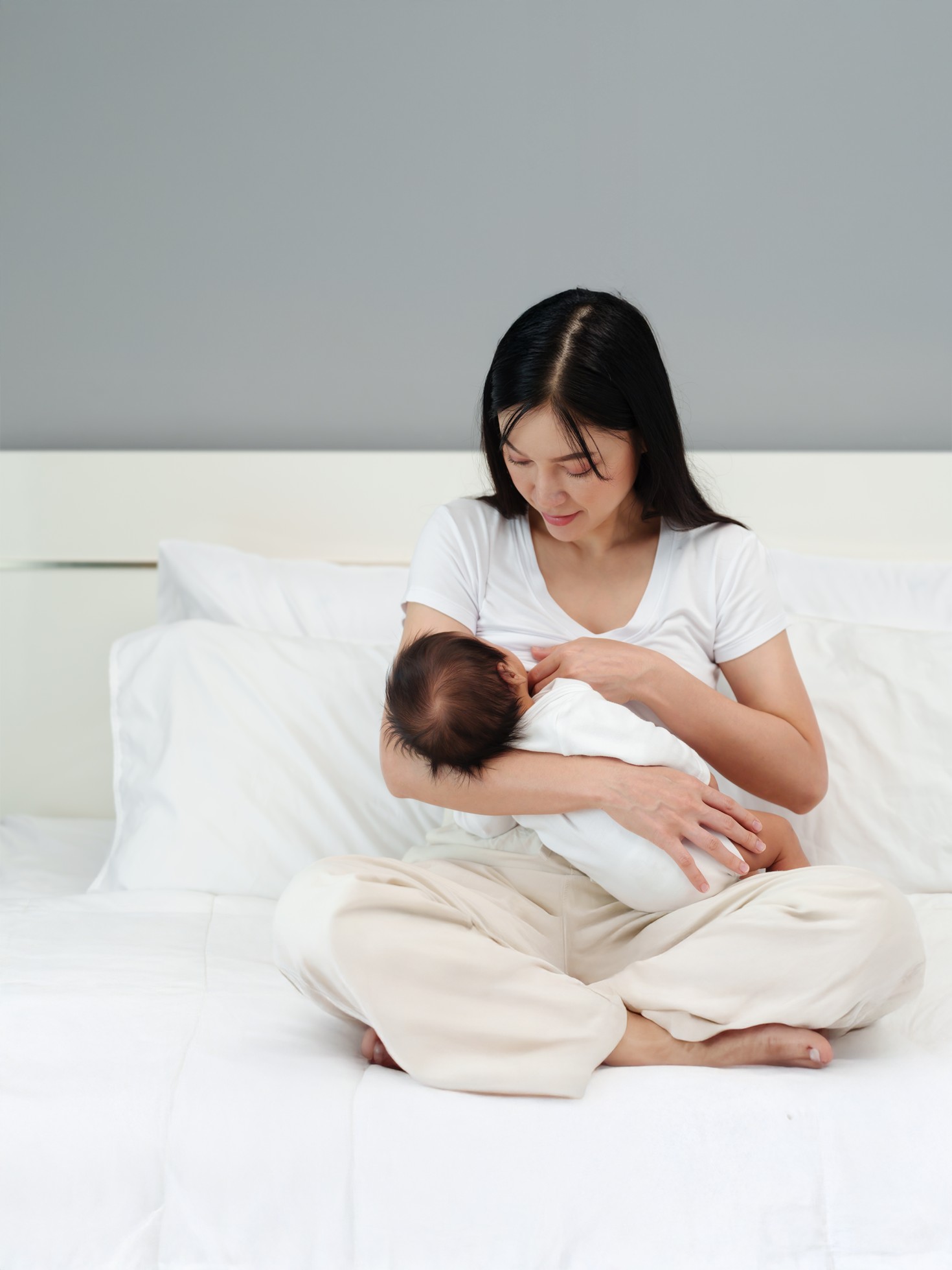 mother breastfeeding newborm baby on a bed