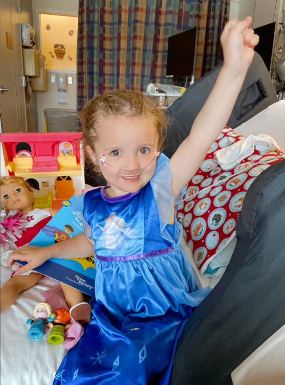 Amelia in a princess dress playing with her toys at the hospital