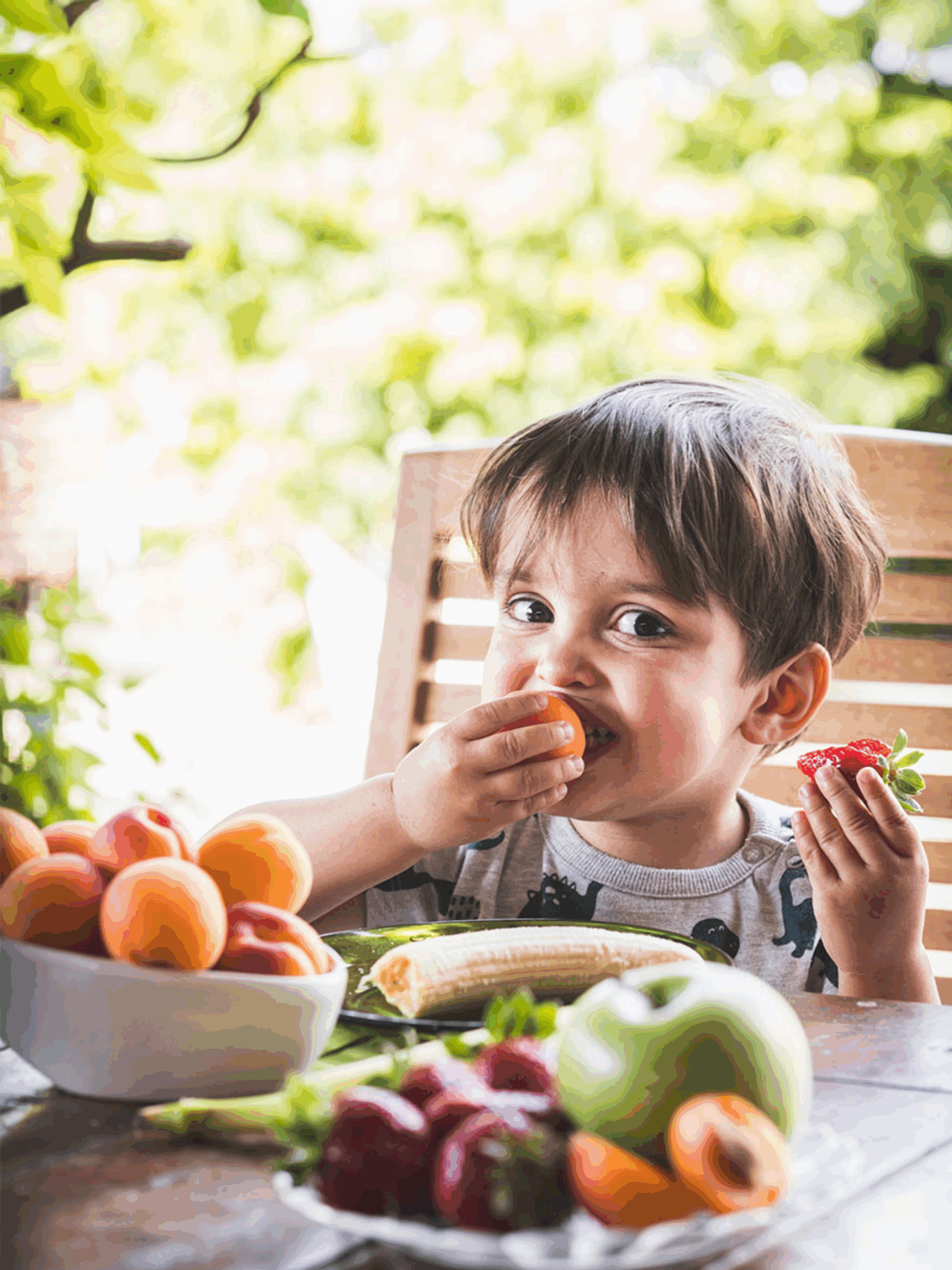 Little boy eating healthy fruits and vegetables