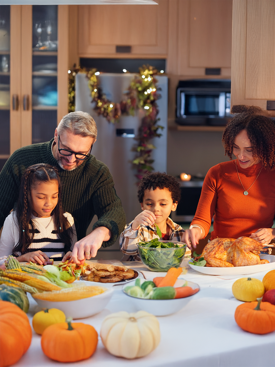 Happy family, helping and children in cooking for thanksgiving event, food and festive holiday. People, interracial parents and happiness for dinner party, meal prep and gathering in home for bonding
