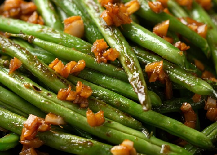 Stir fried garlic, ginger green beans in black bowl