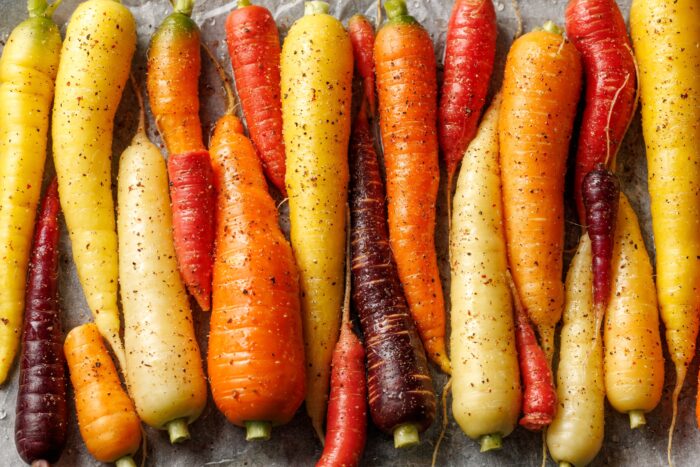 Ready to bake rainbow carrots on a parchment lined baking sheet.