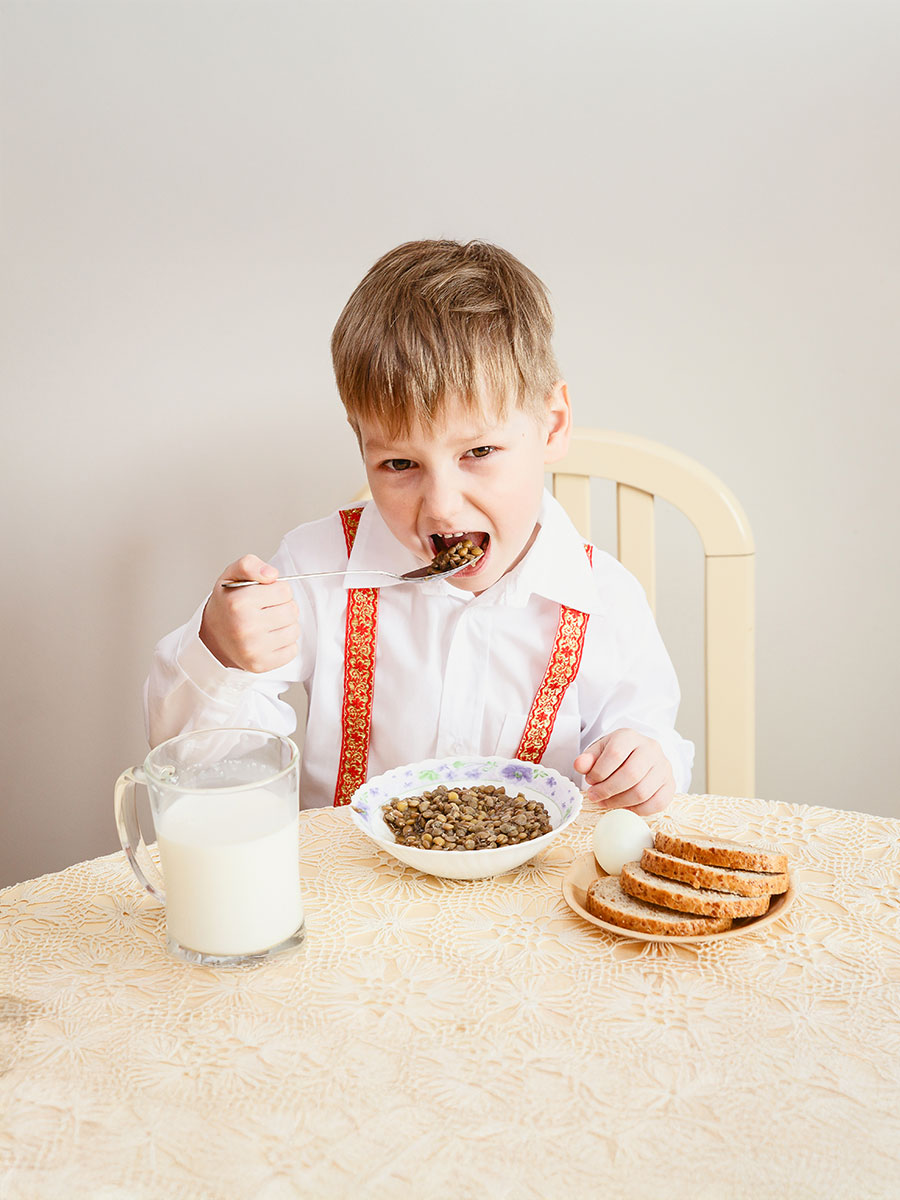 the child sits at the table and eats the lentils, healthy eating, milk, eggs, bread