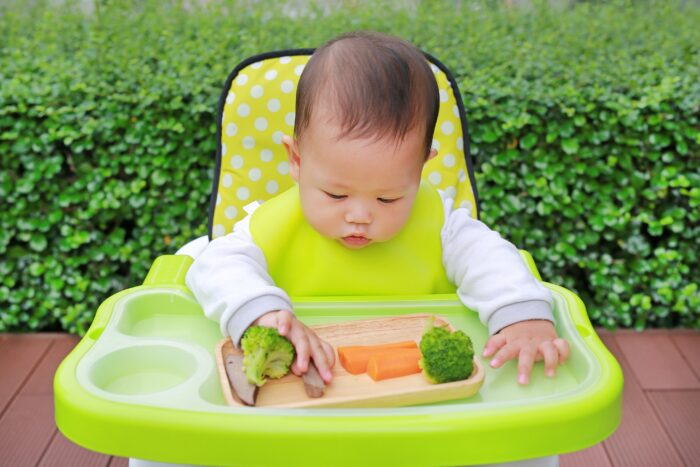 Portrait of newborn baby boy eating by Baby Led Weaning (BLW). Finger foods concept.