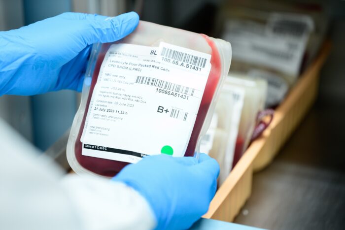 Close up scientist hand holding red blood bag in storage refrigerator at blood bank unit laboratory.Blood bags received from blood donations will be used in patients. Save life medical concept.