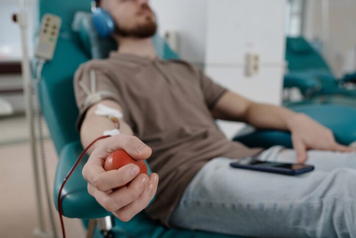 Hand of man squeezing red rubber ball while donating blood in hospital