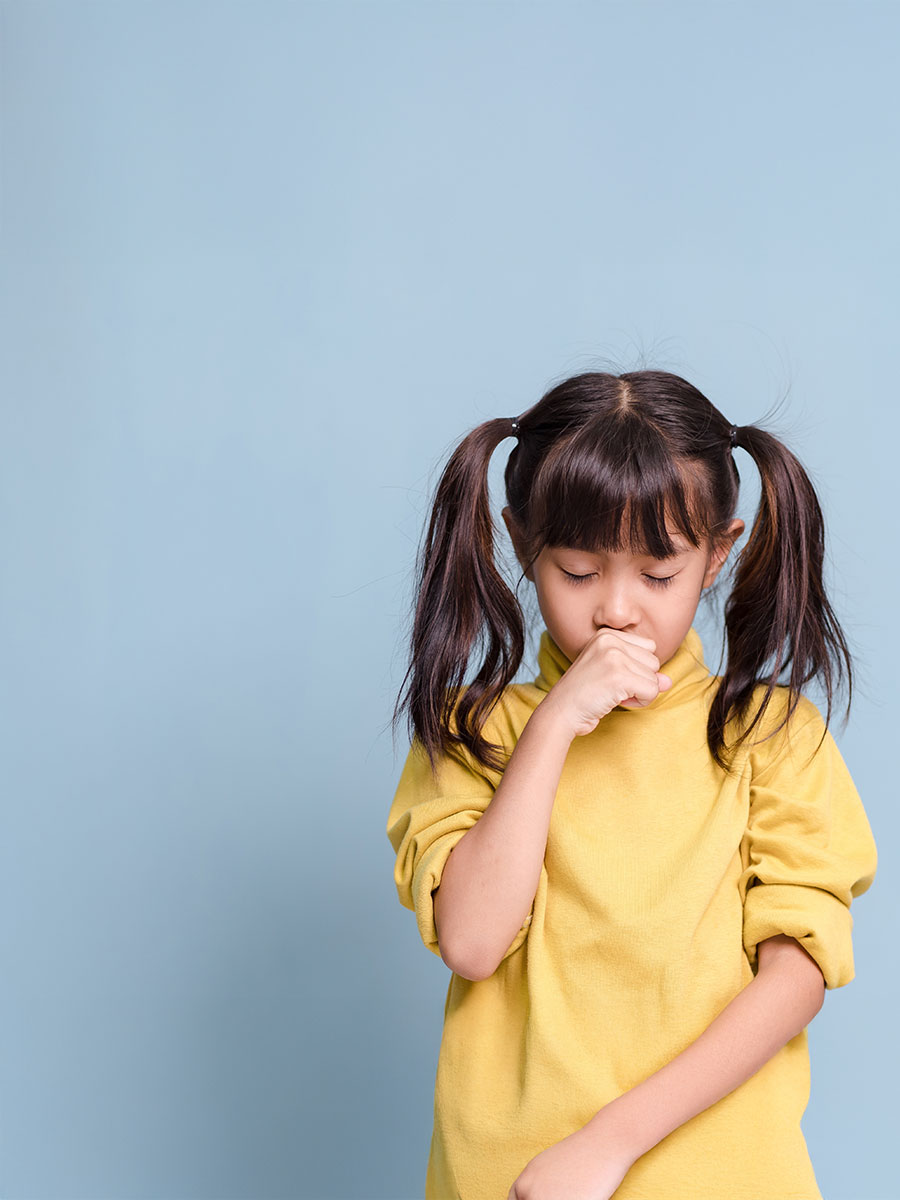 A little girl is coughing, sick, has a fever.