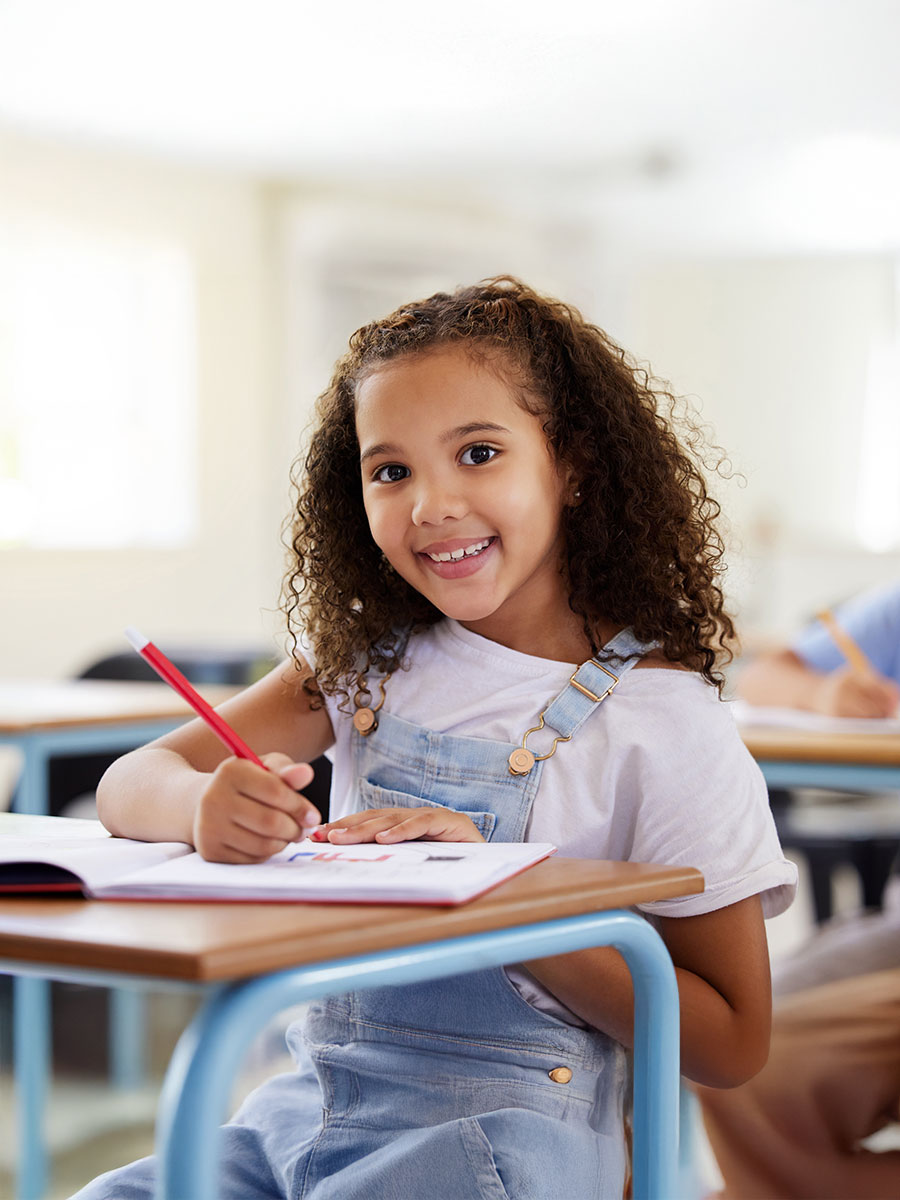 Learning, drawing and portrait of girl in classroom exam, education or studying with book. Preschool smile, development and happy kid or student coloring for creative art in notebook in kindergarten.