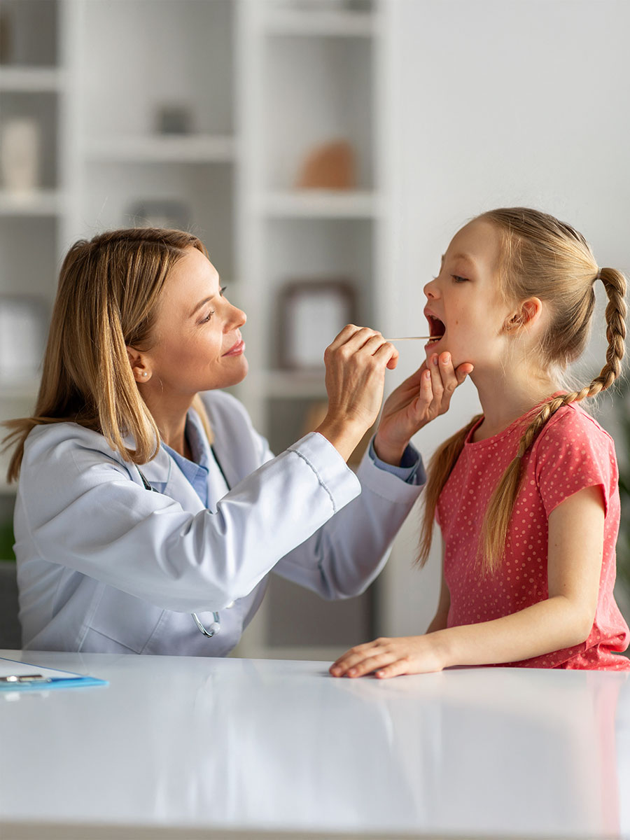 Kids Healthcare. Female doctor pediatrician checking throat of little girl patient, cute female child having checkup in modern clinic, suffering angina or tonsillitis, having strep, closeup