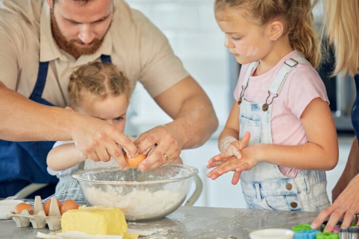 Hands, teaching or family cooking with children in kitchen for child development to prepare cookies. Father, parents or kids siblings learning recipe for bonding, baking or dessert for love in home