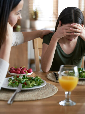 Teen upset when eating dinner and being comforted by mom 