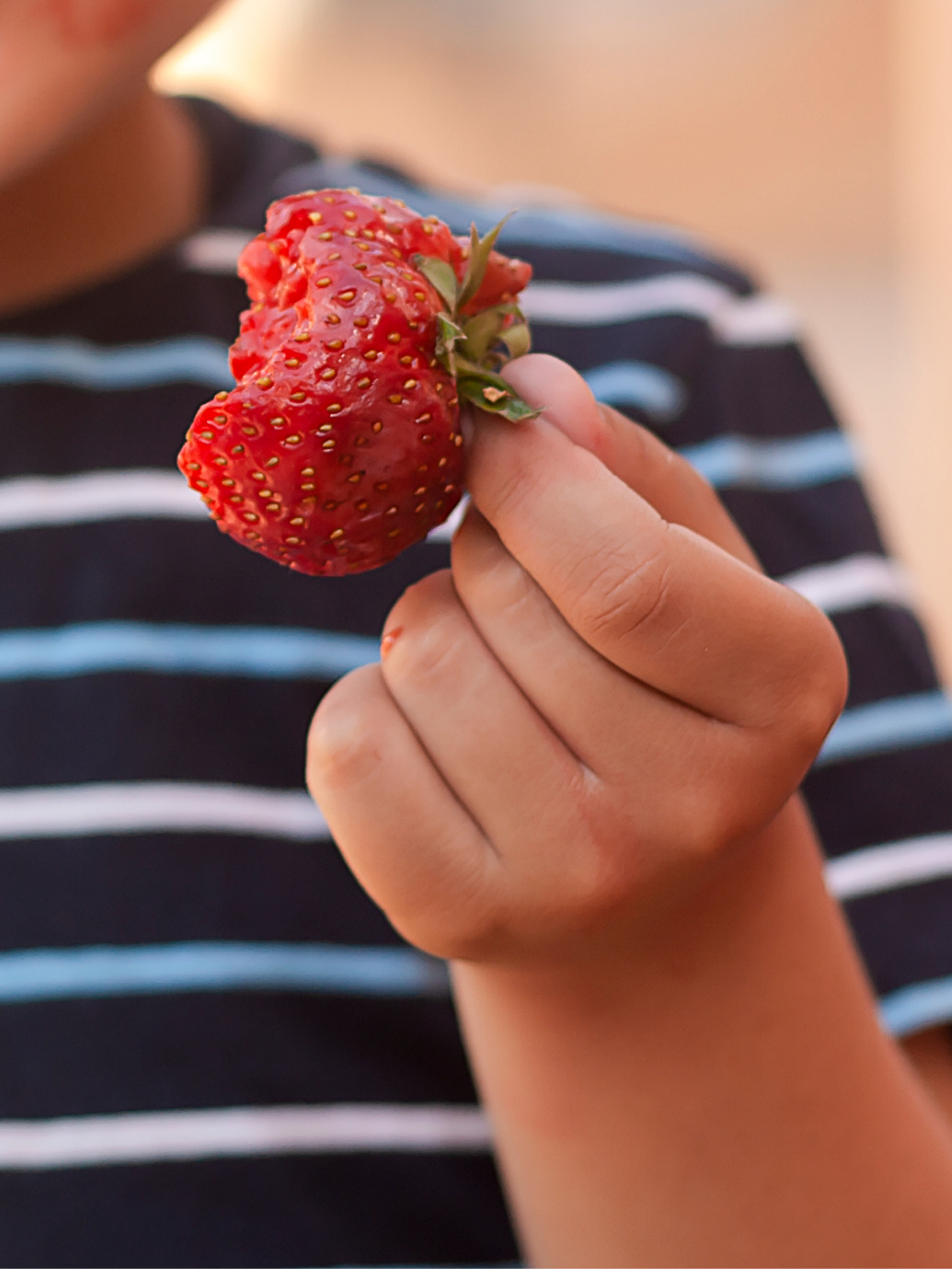 child holding half eaten strawberry