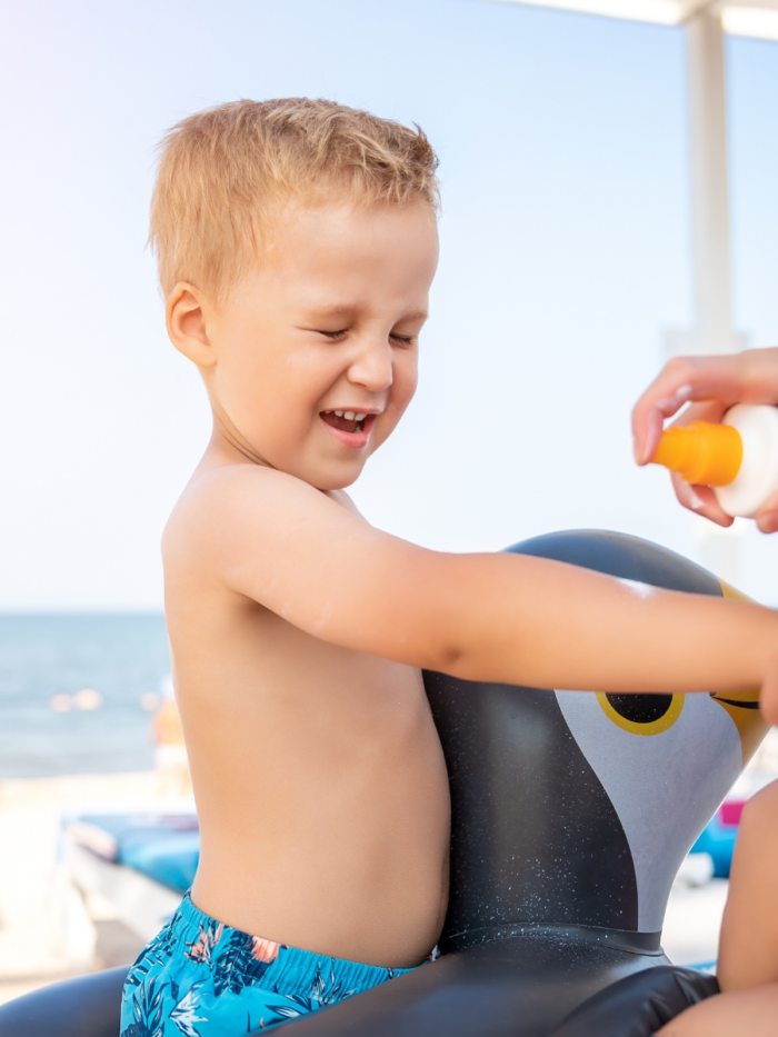 Mother applying sunscreen protection creme on cute little baby boy kid hand. Mum using sunblocking lotion to protect baby from sun during summer sea vacation. Child healthcare travel vacation time.