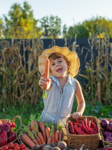 A child at a farmers market with vegetables. Selective focus. Food.