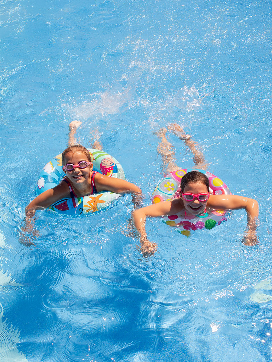Two little girls play and swim in the pool