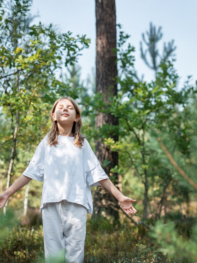 A teenage girl who breathes fresh air and relieves stress in the forest. Dreamy peaceful relaxed girl breathing the fresh air of nature.