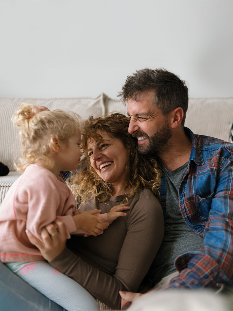 Parents Hugging Toddler Daughter During Relaxing Weekend at Home